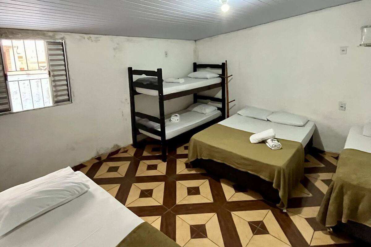 Un dormitorio con literas, una ventana con persianas y suelo estampado.