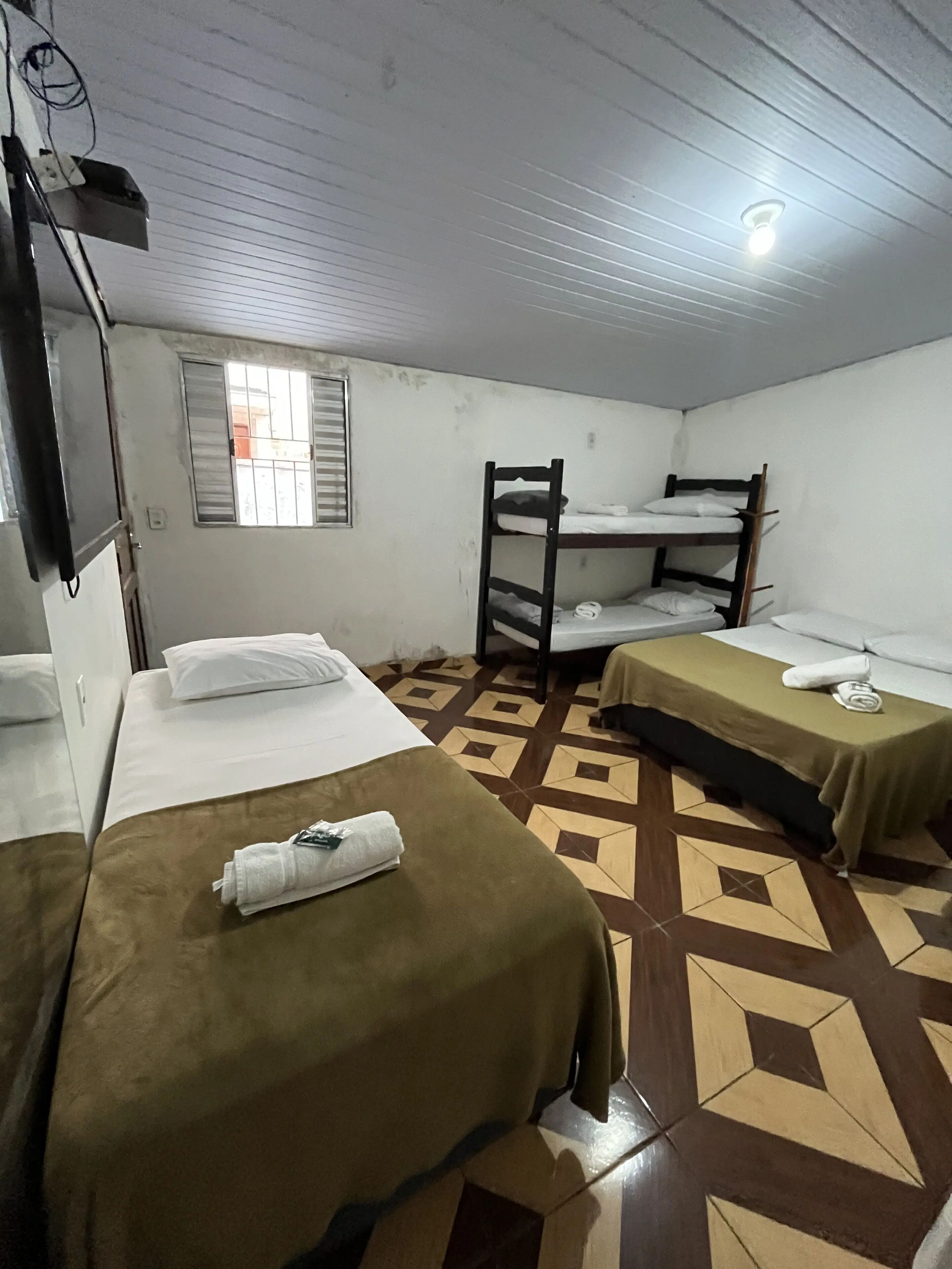 Una habitación con literas, una cama individual y un piso con estampado.