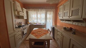 Une cuisine avec des meubles blancs, une cuisinière et une table à manger avec des chaises.
