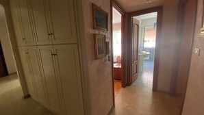 Un couloir avec un placard, une porte donnant sur une salle de bain et un sol carrelé.