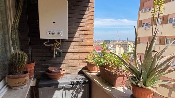 Un balcon agr émenté de plantes en pot, un chauffe-eau et une vue sur le paysage urbain.