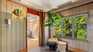 A room with a large window, a potted plant, a wall-mounted light fixture, and a traditional Japanese sliding door.
