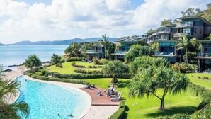 A resort with a swimming pool, lush greenery, and beachfront villas.