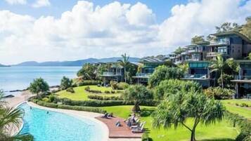 Un complexe hôtelier doté d’une piscine, d’une végétation luxuriante et de villas en bord de mer.