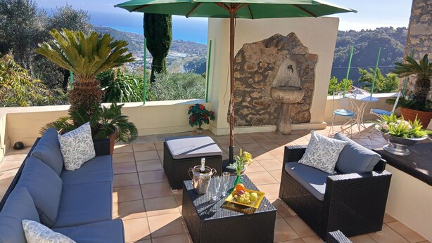 A terrace with outdoor furniture, a stone wall, and a view of the landscape.