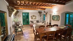 A spacious dining area with a wooden table and chairs, a sofa, and a mirror.