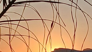 A sunset over the ocean with waves and a distant landmass.