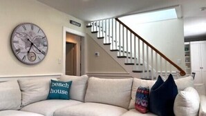 Un salon avec un canapé beige, une horloge et un escalier.
