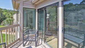 A balcony with a glass door, a metal railing, and a view of the surrounding greenery. - 2382 Lighthouse Tennis: 1 Bedroom Pet Friendly, Free Bikes, Pool, Tennis (Hilton Head Island)