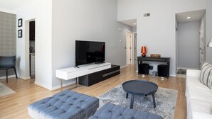 A modern living room with a flat-screen TV, a sofa, a coffee table, and a dining area with a small table and chairs. - 2382 Lighthouse Tennis: 1 Bedroom Pet Friendly, Free Bikes, Pool, Tennis (Hilton Head Island)