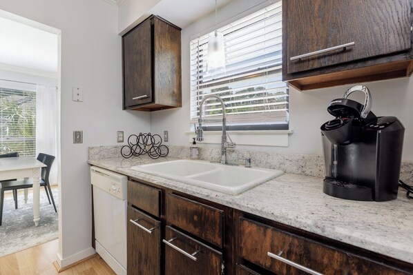 A kitchen with dark wooden cabinets, a white countertop, a double sink, and a coffee maker. - 2382 Lighthouse Tennis: 1 Bedroom Pet Friendly, Free Bikes, Pool, Tennis (Hilton Head Island)