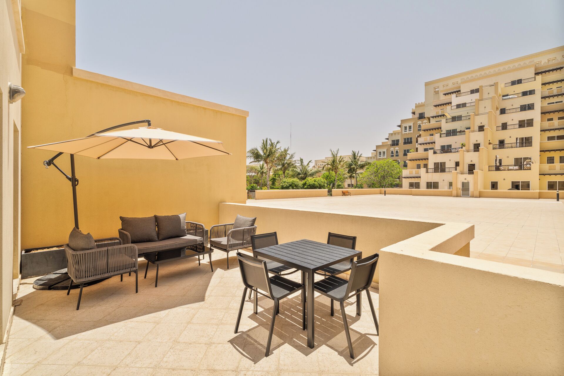 An outdoor patio with a table and chairs, a sofa, and an umbrella.