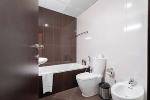 A modern bathroom with a bathtub, toilet, bidet, and sink.