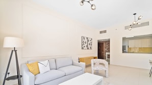 A modern living room with a sofa, a coffee table, a floor lamp, and a dining area with a chair and a table. - Nasma Holiday Homes - Bab Al Bahr Residences (Ras Al Khaimah)
