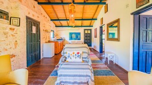 Una camera accogliente con soffitto in legno, un letto con copripiumino decorato, un tavolino bianco e una sedia.