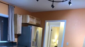 A kitchen with wooden cabinets, a stainless steel refrigerator, a granite countertop, and a sink. - Longhorn Lodge - Extended Stay (Great Falls)