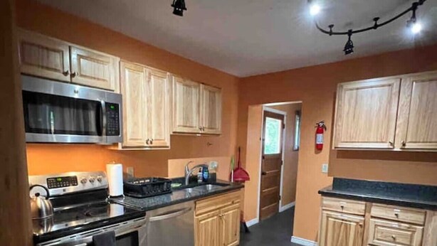 A kitchen with wooden cabinets, a stainless steel oven, a microwave, and a gas stove. - Longhorn Lodge - Extended Stay (Great Falls)