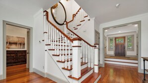 A staircase with white balusters and wooden steps, leading to a landing with a door. - 5 Bedroom Squam Lake Home with Dock Paddleboard Kayak and canoe Sleeps 17 (Center Sandwich)