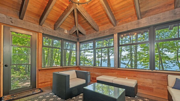 A cozy room with large windows, wicker furniture, and a wooden ceiling. - 5 Bedroom Squam Lake Home with Dock Paddleboard Kayak and canoe Sleeps 17 (Center Sandwich)
