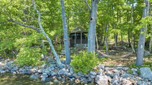 A cabin surrounded by trees and a rocky stream. - 5 Bedroom Squam Lake Home with Dock Paddleboard Kayak and canoe Sleeps 17 (Center Sandwich)