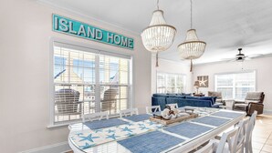 A dining area with a glass table, blue placemats, and a sign reading "ISLAND HOME". - Family-Friendly w/ Private Pool, Gulf Views, Dogs OK! (St. George Island)