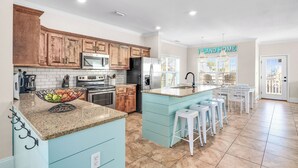 A kitchen with wooden cabinets, a granite countertop, a stainless steel refrigerator, and a sign that reads "ISLAND HOME". - Family-Friendly w/ Private Pool, Gulf Views, Dogs OK! (St. George Island)