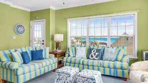 A living room with two striped sofas, a white armchair, and a patterned ottoman. - Family-Friendly w/ Private Pool, Gulf Views, Dogs OK! (St. George Island)