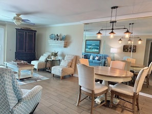 A living room with a dining area, a ceiling fan, and a chandelier.
