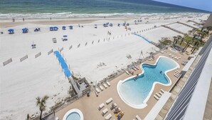 Un resort en la playa con piscina, sombrillas y sillas.