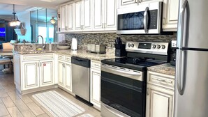 Una cocina moderna con armarios blancos, electrodomésticos de acero inoxidable y un salpicadero de azulejos.
