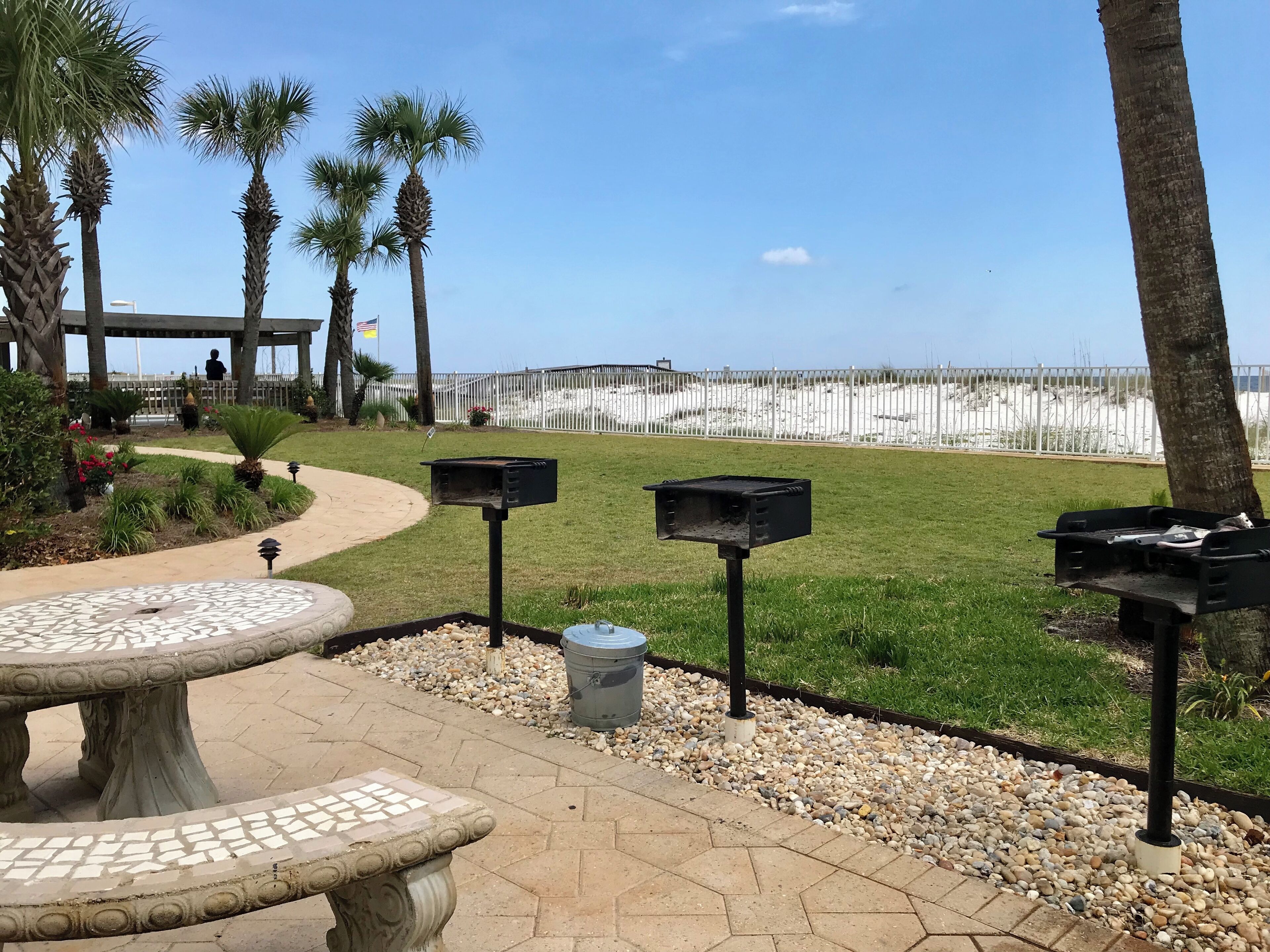 Eine Terrasse mit einem Tisch aus Mosaikfliesen, einem Weg und Blick auf den Strand.