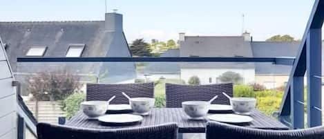 A balcony with a table and chairs, overlooking a residential area.