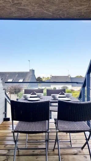 A balcony with a table and chairs, overlooking a residential area.