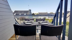 A balcony with a table set for four, overlooking a residential area.