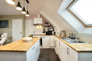 A compact kitchen with a wooden countertop, built-in appliances, and a skylight.