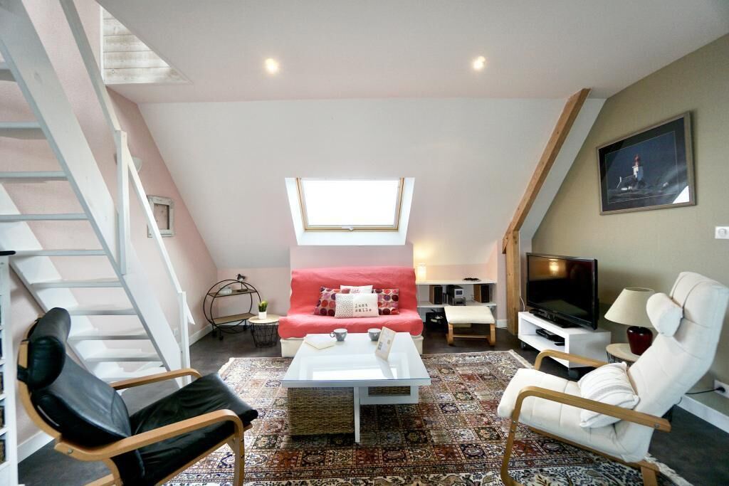Una sala de estar con sofá, mesa de centro, televisor y zona de asientos.