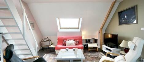 Una sala de estar con sofá, mesa de centro, televisor y zona de asientos.