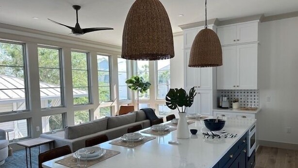 Een moderne keuken met een groot eiland, hanglampen en uitzicht op de omgeving.