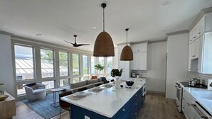 Een moderne keuken met een groot eiland, witte kasten en een zithoek met een bank en stoelen.