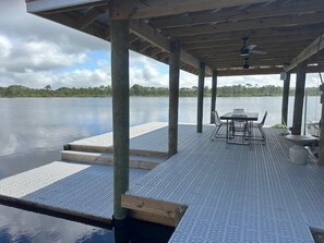 A wooden deck with a table and chairs, overlooking a calm body of water. - 127 Banfill Street 2 bed 2 bath private pool, dock on Grayton Lake (Santa Rosa Beach)