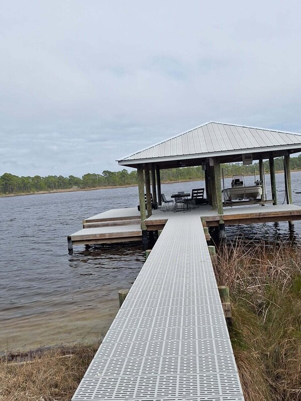 A dock extending into a body of water with a covered seating area and a small boat. - 127 Banfill Street 2 bed 2 bath private pool, dock on Grayton Lake (Santa Rosa Beach)