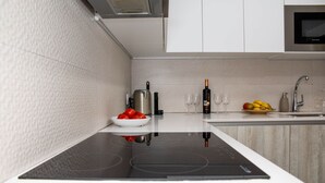 Une cuisine moderne équipée d’une cuisinière intégrée, d’un saladier de tomates, d’une bouteille d’huile d’olive et d’une assiette de fruits.