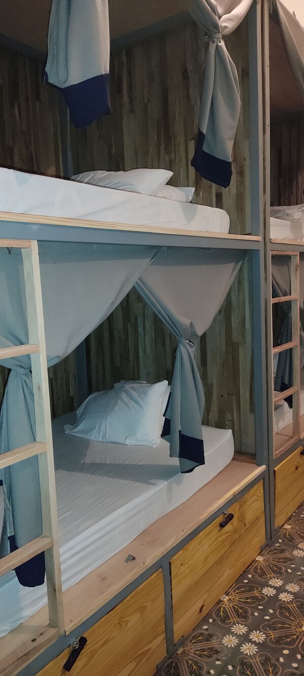 A bunk bed with a canopy, wooden walls, and a patterned floor.