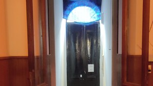 A hallway with a patterned floor, a blue ceiling, and a closed door at the end. - MEDITERRANEO HOSTEL (Asunción)