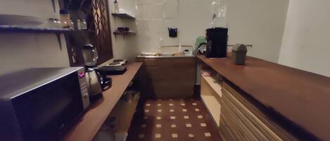 A kitchen with a microwave, coffee maker, and a small sink.