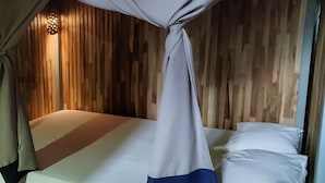 A single bed with a canopy, wooden walls, and a small light fixture above it. - MEDITERRANEO HOSTEL (Asunción)