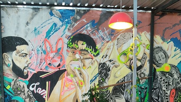 A restaurant with a mural on the wall, wooden furniture, and a glass on a coaster. - MEDITERRANEO HOSTEL (Asunción)