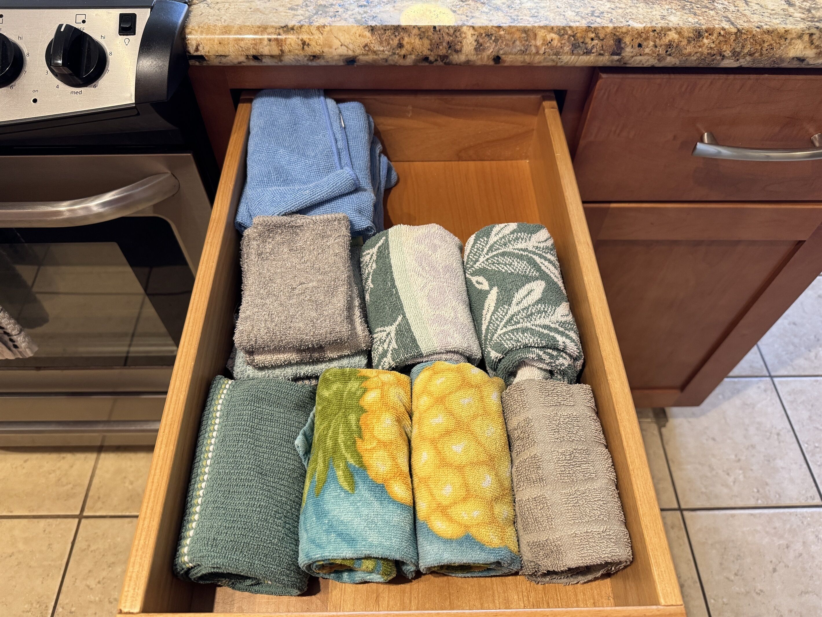 A kitchen drawer with various folded towels.