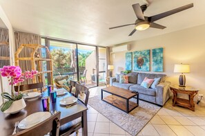 A spacious living area with a dining table, sofa, and a ceiling fan. - Steps to Kamaole Beach | Pickleball | Saltwater Pool | AC King Bed | Ground Flr (Kihei)