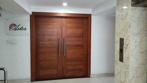 A wooden wardrobe with two doors and handles, a marble wall, and a sign with the word "Aster". - Hotel Autumn Crocus (Guwahati)